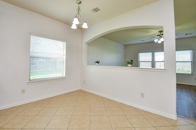 tiled spare room featuring a ceiling fan, a chandelier, baseboards, and arched walkways