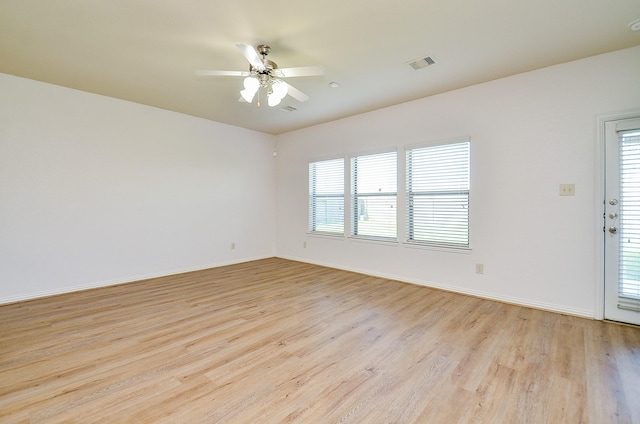 spare room featuring light wood finished floors, ceiling fan, and baseboards