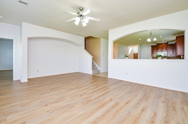 unfurnished living room featuring light wood-style flooring, ceiling fan, a chandelier, and stairs