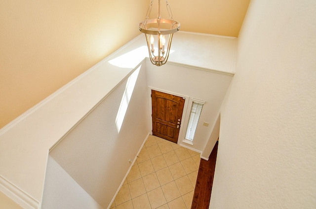 foyer with a chandelier, light tile patterned flooring, and baseboards