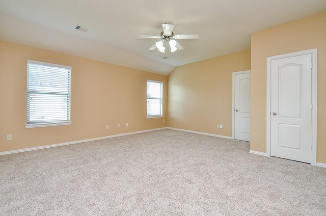 spare room featuring ceiling fan, carpet flooring, baseboards, and lofted ceiling