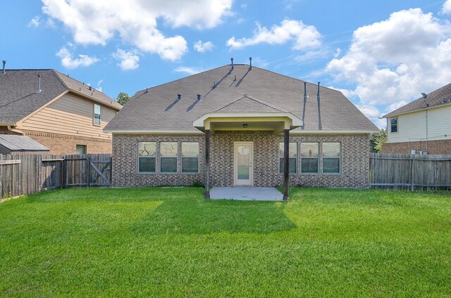 rear view of property featuring a patio area, brick siding, and roof with shingles
