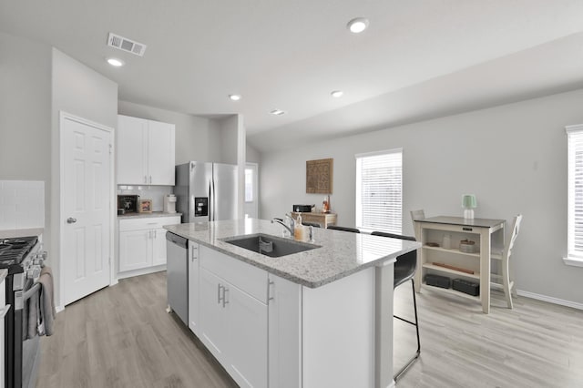 8230 Red Spruce St, Magnolia, TX 77354 - kitchen with appliances with stainless steel finishes, a sink, light wood finished floors, a kitchen island with sink, and recessed lighting