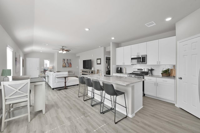 8230 Red Spruce St, Magnolia, TX 77354 - kitchen with appliances with stainless steel finishes, a breakfast bar area, decorative backsplash, white cabinetry, and recessed lighting