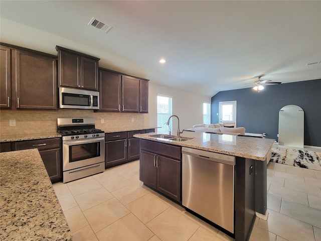 4931 Marina Shores Ct, Katy, TX 77493 - kitchen with stainless steel appliances, a sink, open floor plan, backsplash, and arched walkways