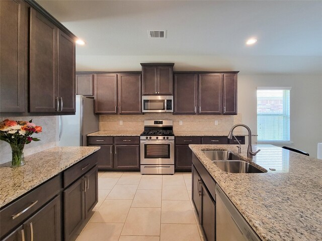 4931 Marina Shores Ct, Katy, TX 77493 - kitchen with stainless steel appliances, a sink, tasteful backsplash, light stone countertops, and dark brown cabinets