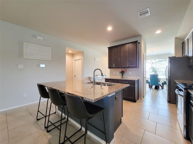 4931 Marina Shores Ct, Katy, TX 77493 - kitchen with stainless steel range with gas cooktop, a sink, light stone counters, a kitchen bar, and recessed lighting