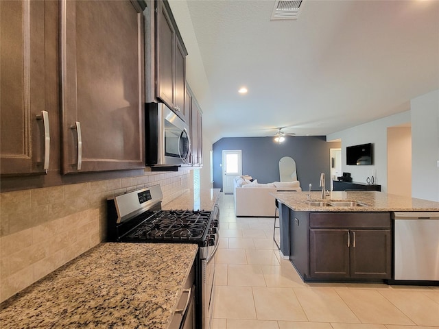 4931 Marina Shores Ct, Katy, TX 77493 - kitchen with appliances with stainless steel finishes, open floor plan, a ceiling fan, a sink, and backsplash