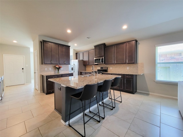 4931 Marina Shores Ct, Katy, TX 77493 - kitchen featuring stainless steel appliances, tasteful backsplash, dark brown cabinets, light stone countertops, and light tile patterned floors