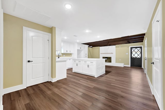 kitchen with open floor plan, a large fireplace, dark wood-style flooring, recessed lighting, and white cabinets