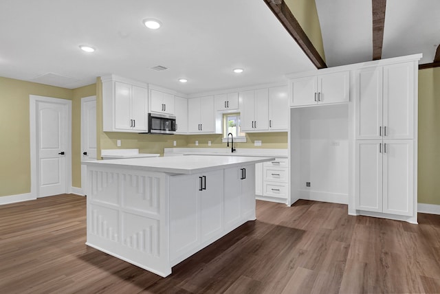 kitchen with stainless steel microwave, a sink, white cabinets, and recessed lighting