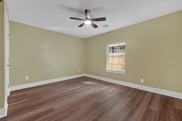 unfurnished room with wood finished floors, a ceiling fan, and baseboards