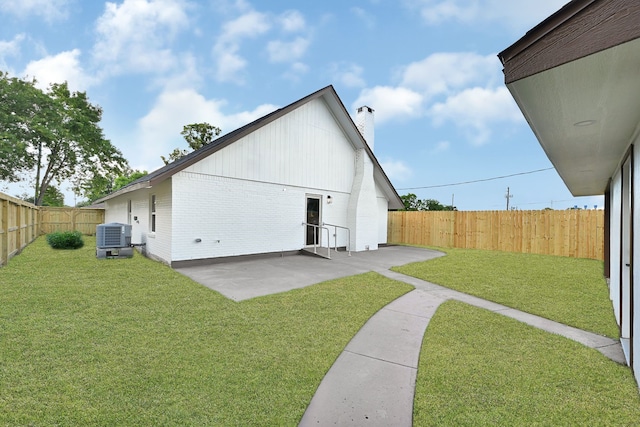 view of side of property featuring a chimney, cooling unit, a patio area, and brick siding
