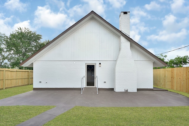back of house with a patio area, a chimney, and brick siding