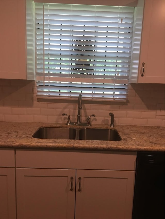 kitchen featuring a sink, white cabinets, plenty of natural light, and backsplash