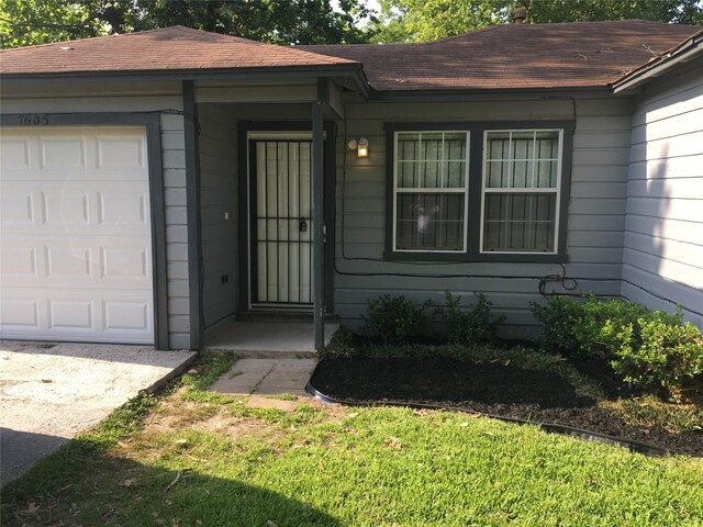 entrance to property featuring roof with shingles and a garage