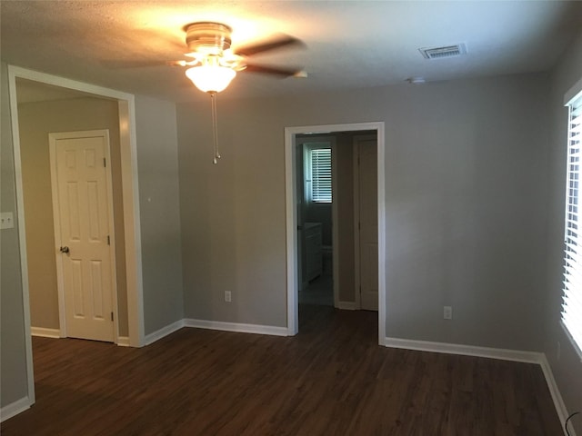 spare room featuring a ceiling fan, dark wood-style flooring, and baseboards