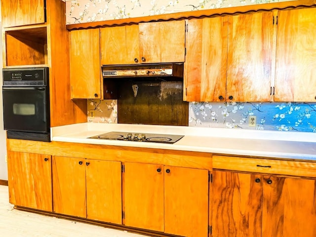 1085 Duke Rd, Kennard, TX 75847 - kitchen featuring black appliances, light countertops, under cabinet range hood, brown cabinets, and wallpapered walls