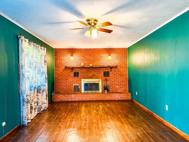 1085 Duke Rd, Kennard, TX 75847 - unfurnished living room featuring hardwood / wood-style flooring, ceiling fan, ornamental molding, a brick fireplace, and wood walls