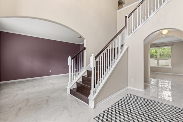 20106 Pinehaven Ln, Spring, TX 77379 - stairway featuring marble look tile flooring, arched walkways, ornamental molding, baseboards, and a high ceiling