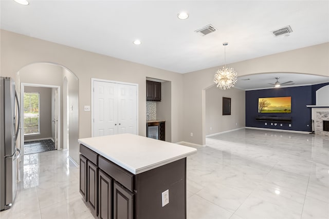 20106 Pinehaven Ln, Spring, TX 77379 - kitchen with arched walkways, freestanding refrigerator, light marble finish floors, a ceiling fan, and dark brown cabinets