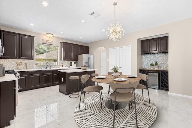 20106 Pinehaven Ln, Spring, TX 77379 - kitchen featuring arched walkways, a center island, light marble finish floors, light countertops, and a chandelier
