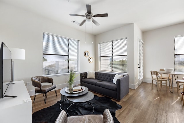 living room with wood finished floors, a ceiling fan, and baseboards