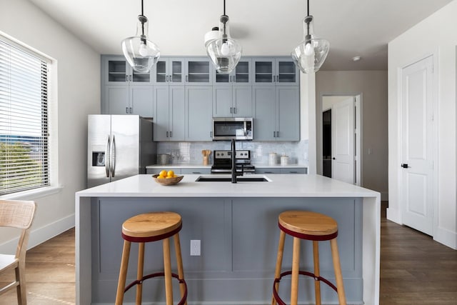 kitchen featuring appliances with stainless steel finishes, a sink, backsplash, and dark wood-style flooring