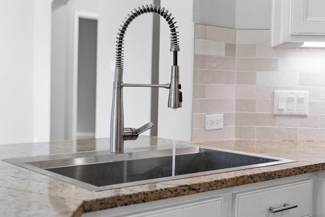 12506 Emerald Springs Dr, Pearland, TX 77584 - kitchen view of white cabinets, decorative backsplash, a sink, and light stone countertops