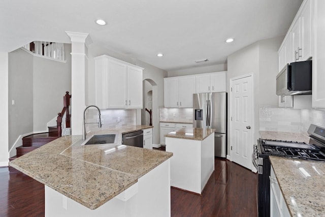 12506 Emerald Springs Dr, Pearland, TX 77584 - kitchen featuring appliances with stainless steel finishes, a sink, a center island, a peninsula, and arched walkways