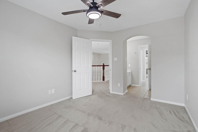12506 Emerald Springs Dr, Pearland, TX 77584 - spare room featuring arched walkways, light carpet, ceiling fan, and baseboards