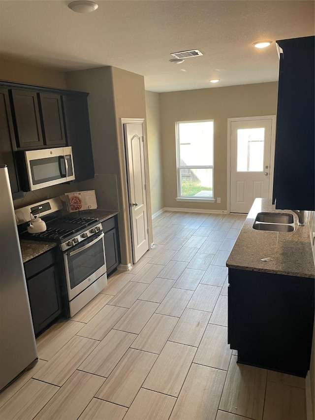 3230 Harmony Creek Ln, Spring, TX 77386 - kitchen featuring appliances with stainless steel finishes, a sink, dark stone counters, wood finish floors, and baseboards