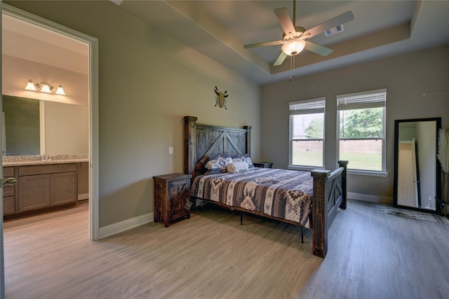 26495 Pin Oak Dr, Hempstead, TX 77445 - bedroom with a raised ceiling, light wood finished floors, baseboards, and connected bathroom