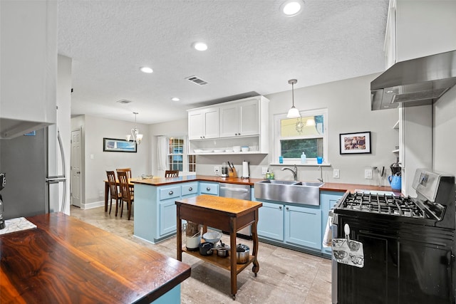 16107 York Minster Dr, Spring, TX 77379 - kitchen with a sink, wooden counters, stainless steel appliances, wall chimney range hood, and blue cabinetry