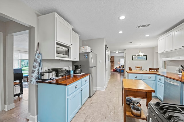 16107 York Minster Dr, Spring, TX 77379 - kitchen with wooden counters, blue cabinetry, stainless steel appliances, a textured ceiling, and white cabinets