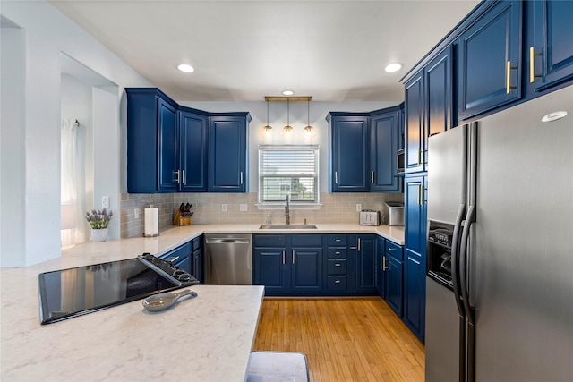 4114 Courageous Ln, Galveston, TX 77554 - kitchen featuring stainless steel appliances, a sink, blue cabinets, backsplash, and light wood-type flooring
