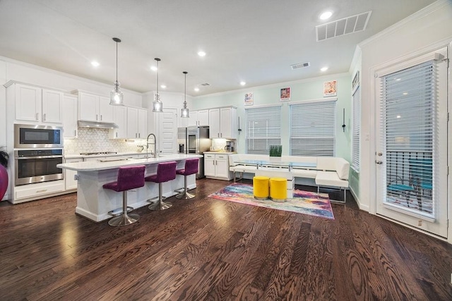 4008 Centre Glen Dr, Houston, TX 77043 - kitchen featuring appliances with stainless steel finishes, light countertops, under cabinet range hood, ornamental molding, and white cabinetry