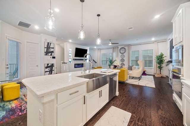 4008 Centre Glen Dr, Houston, TX 77043 - kitchen with stainless steel appliances, a sink, dark wood-style floors, a ceiling fan, and light stone countertops