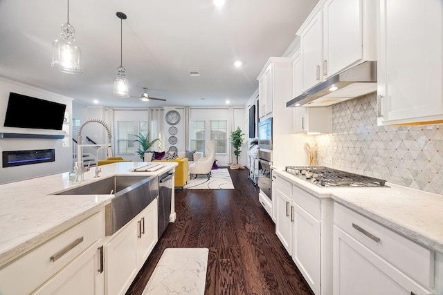 4008 Centre Glen Dr, Houston, TX 77043 - kitchen featuring under cabinet range hood, appliances with stainless steel finishes, a sink, dark wood-type flooring, and open floor plan
