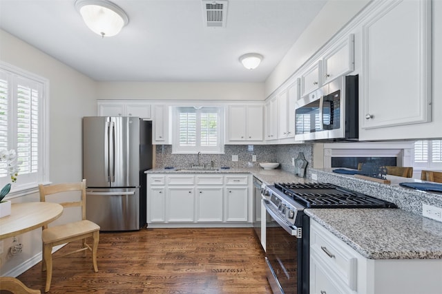 407 W Main St, Brenham, TX 77833 - kitchen with appliances with stainless steel finishes, a sink, white cabinets, and dark wood-style flooring