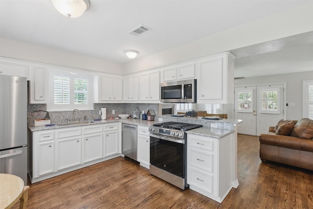 407 W Main St, Brenham, TX 77833 - kitchen with stainless steel appliances, a sink, open floor plan, white cabinetry, and dark wood-style floors
