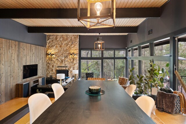827 Magnolia St, Livingston, TX 77351 - dining area with wooden ceiling with exposed beams, a fireplace, plenty of natural light, wood walls, and a chandelier