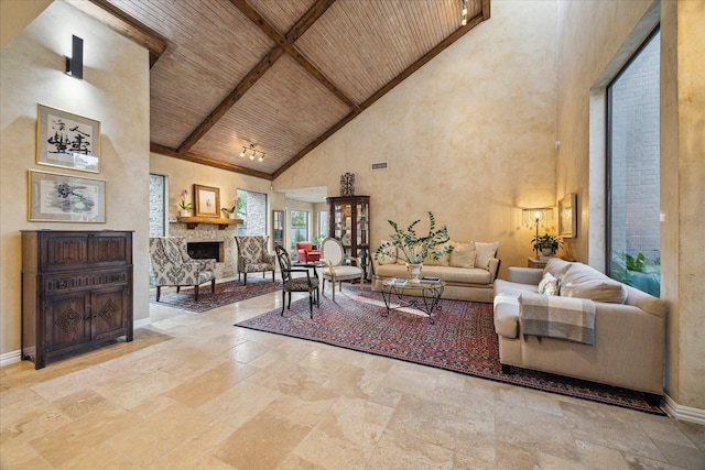 living room with stone tile flooring, high vaulted ceiling, wood ceiling, a fireplace, and beam ceiling