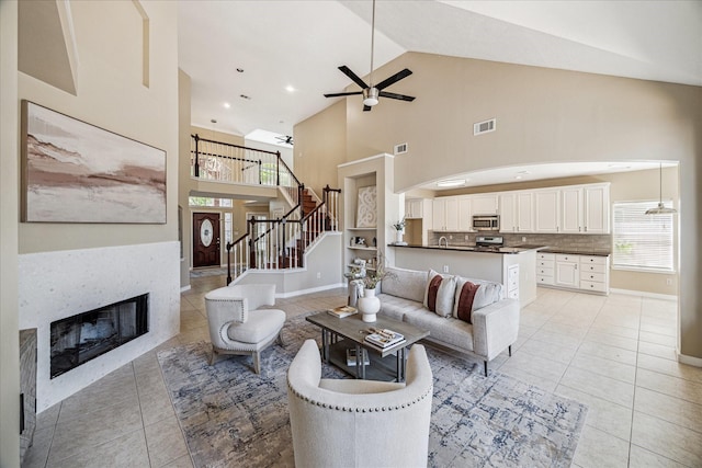 17426 Little Riata Dr, Houston, TX 77095 - living area featuring light tile patterned flooring, high vaulted ceiling, a ceiling fan, a glass covered fireplace, and stairway