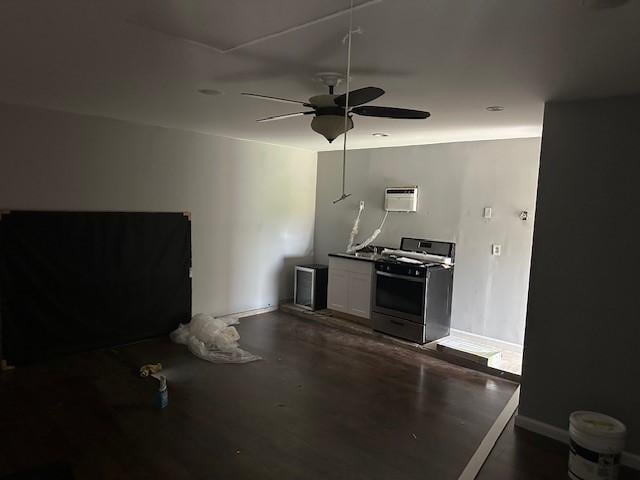 kitchen featuring gas range, a ceiling fan, a wall mounted AC, baseboards, and white cabinetry