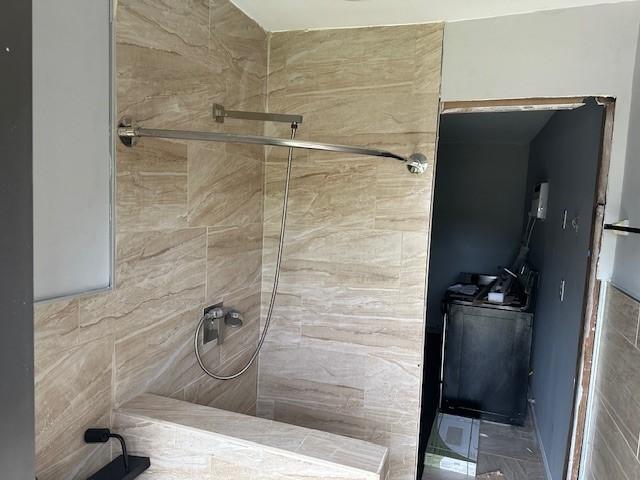 full bath featuring a tile shower and washer / dryer
