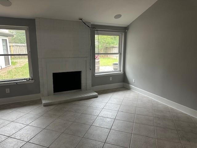 unfurnished living room with healthy amount of natural light, tile patterned floors, and a fireplace