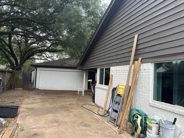 view of side of property with brick siding, fence, and a garage
