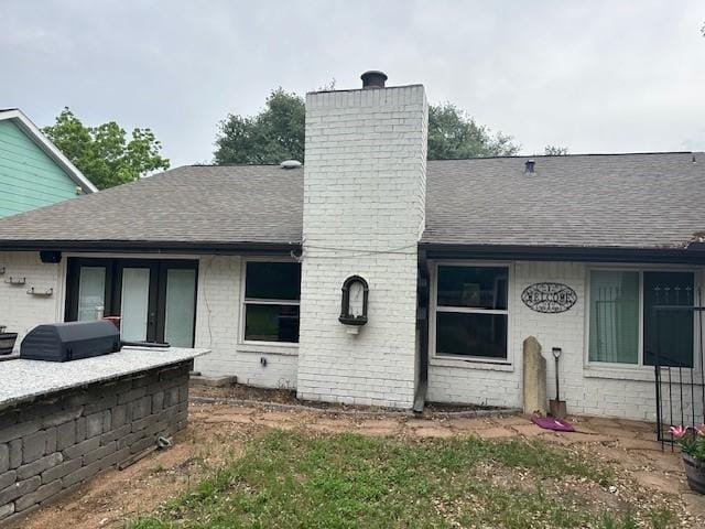 back of property featuring a shingled roof and a chimney