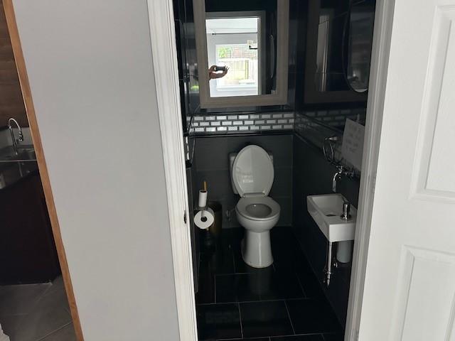 bathroom with toilet, tile patterned flooring, a sink, and tile walls